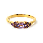 Gold ring with oval amethyst center and purple gemstone accents, elegant handmade jewelry