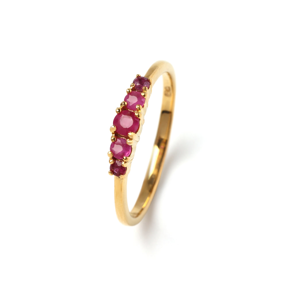 Close-up of 925 sterling silver ruby ring with gold finish and prong-set gemstones by Jewelry by Crimson