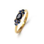 Gold ring with oval sapphire center and round blue gemstones, elegant gemstone jewelry design
