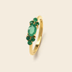 Gold ring with green gemstones on a white background
