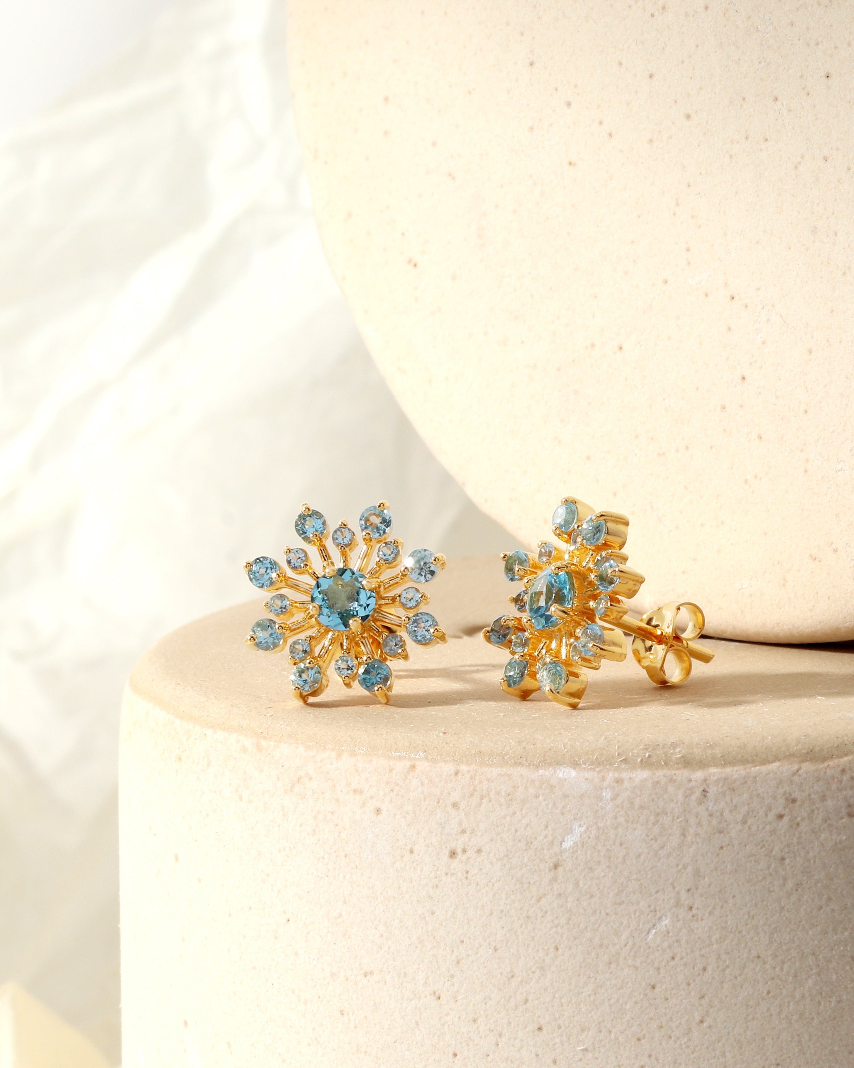 Sky-blue topaz snowflake earrings in gold — side view