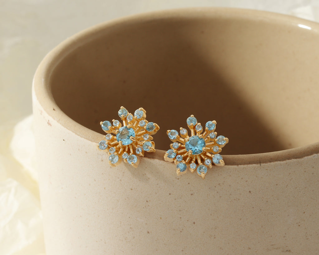 Flower-inspired blue topaz gemstone studs in gold — pair view