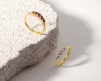 Two gold rings displayed on a white surface next to a textured stone slab. 