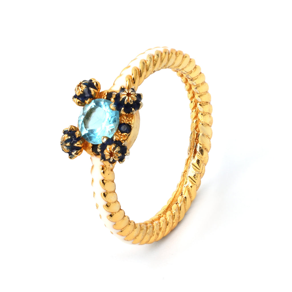 Handcrafted blue topaz ring with white enamel floral accents
