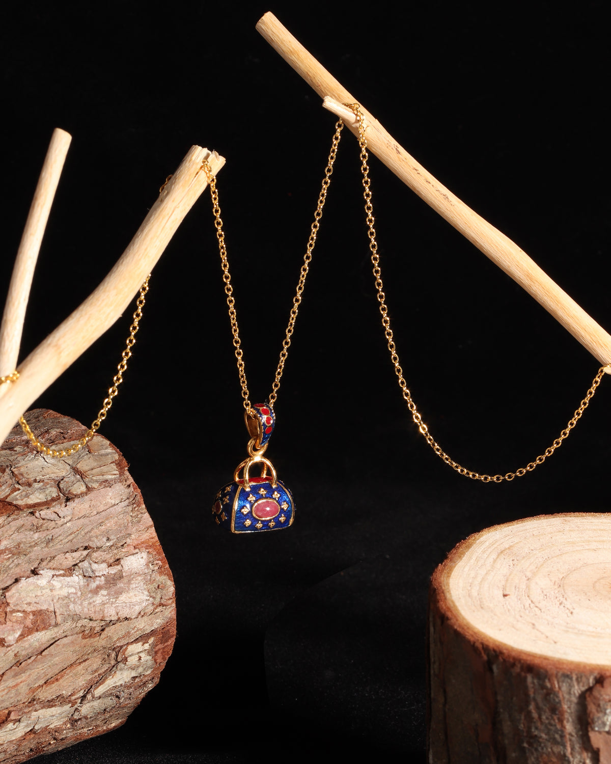 A gold chain necklace with a decorative padlock pendant, displayed on a black background with rustic wood props.