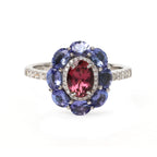 Elegant sterling silver ring with oval red gemstone, blue tanzanites, and diamond accents