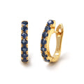 Close-up of 925 sterling silver sapphire hoop earrings with gold finish and prong-set blue sapphires by Jewelry by Crimson