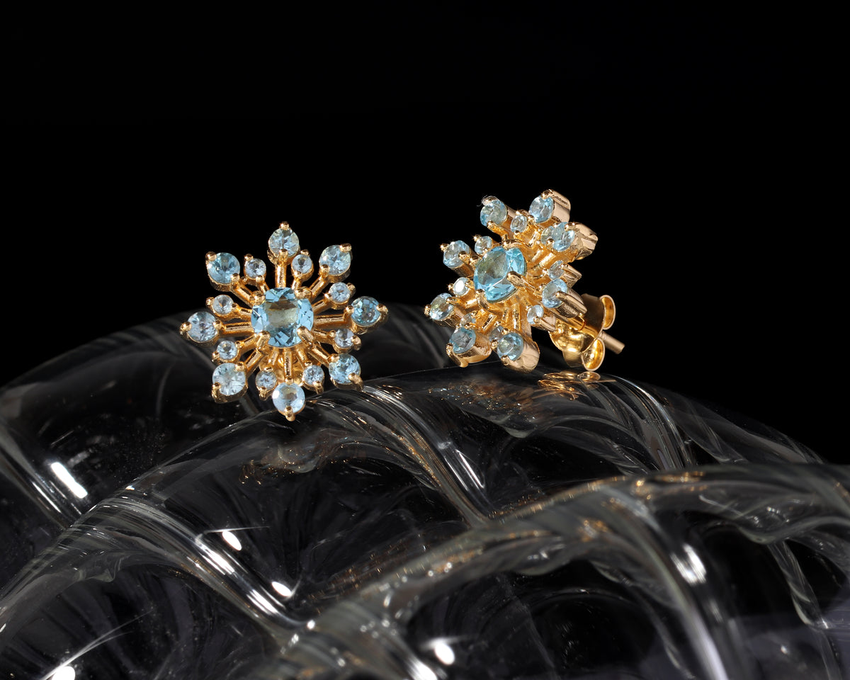 Blue topaz snowflake stud earrings in 18K gold — display view