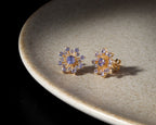 Flower-inspired tanzanite gemstone studs in gold — pair view
