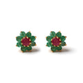 Close-up of 925 sterling silver stud earrings with ruby center and emerald halo, gold finish by Jewelry by Crimson