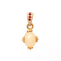 Gold-tone pendant with oval cream stone, red gem accents, and white enamel details, elegant handcrafted jewelry