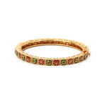 Gold bangle with red and green enamel geometric patterns and gemstone accents, elegant handcrafted jewelry