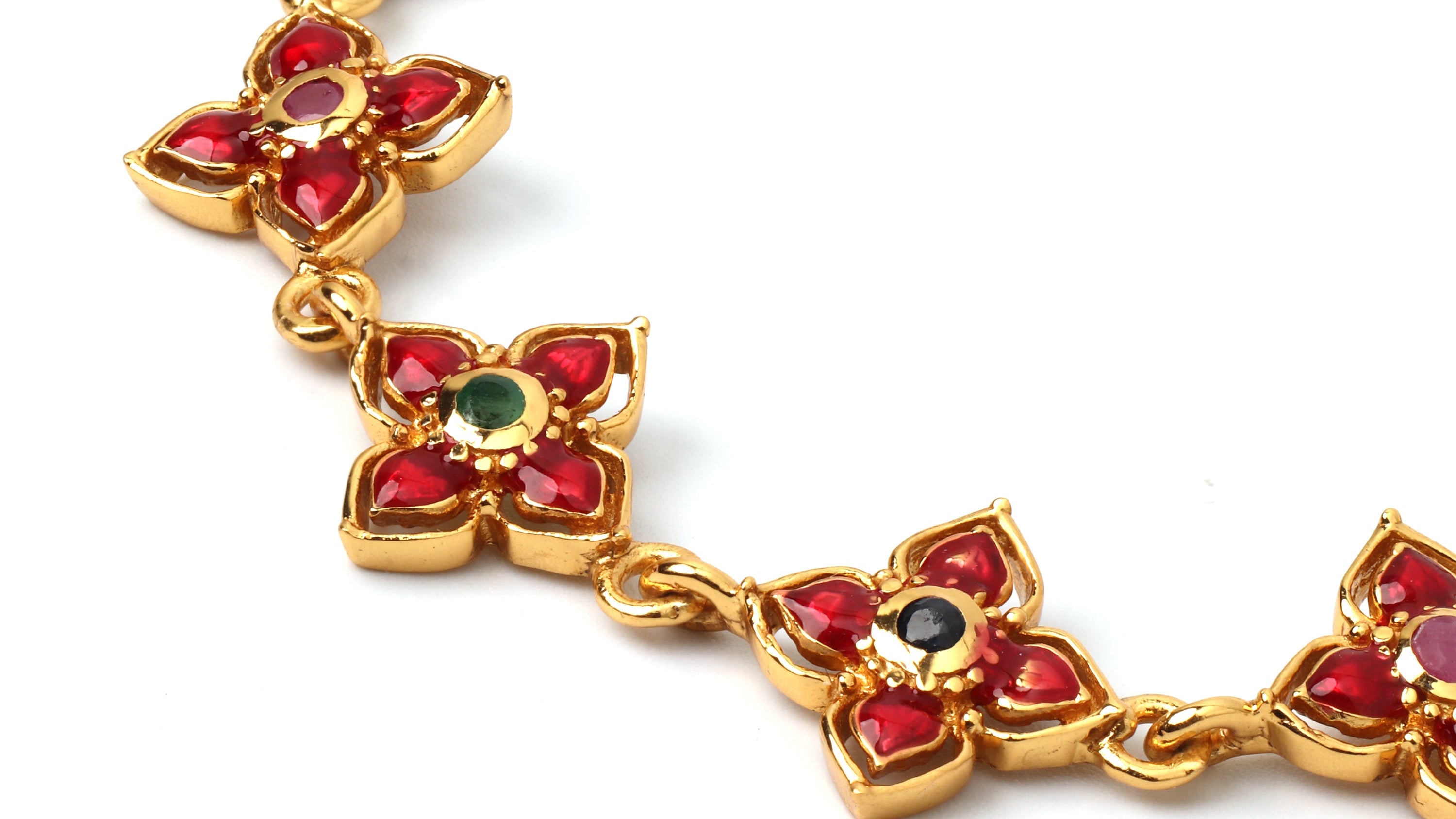Gold bracelet with emerald, ruby and sapphire on a white background