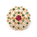 Gold ring with central ruby, emerald accents, and diamond details in floral enamel design