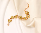 A gold-tone chain bracelet with five oval links featuring textured, glittery yellow inlay, displayed on draped white satin fabric.