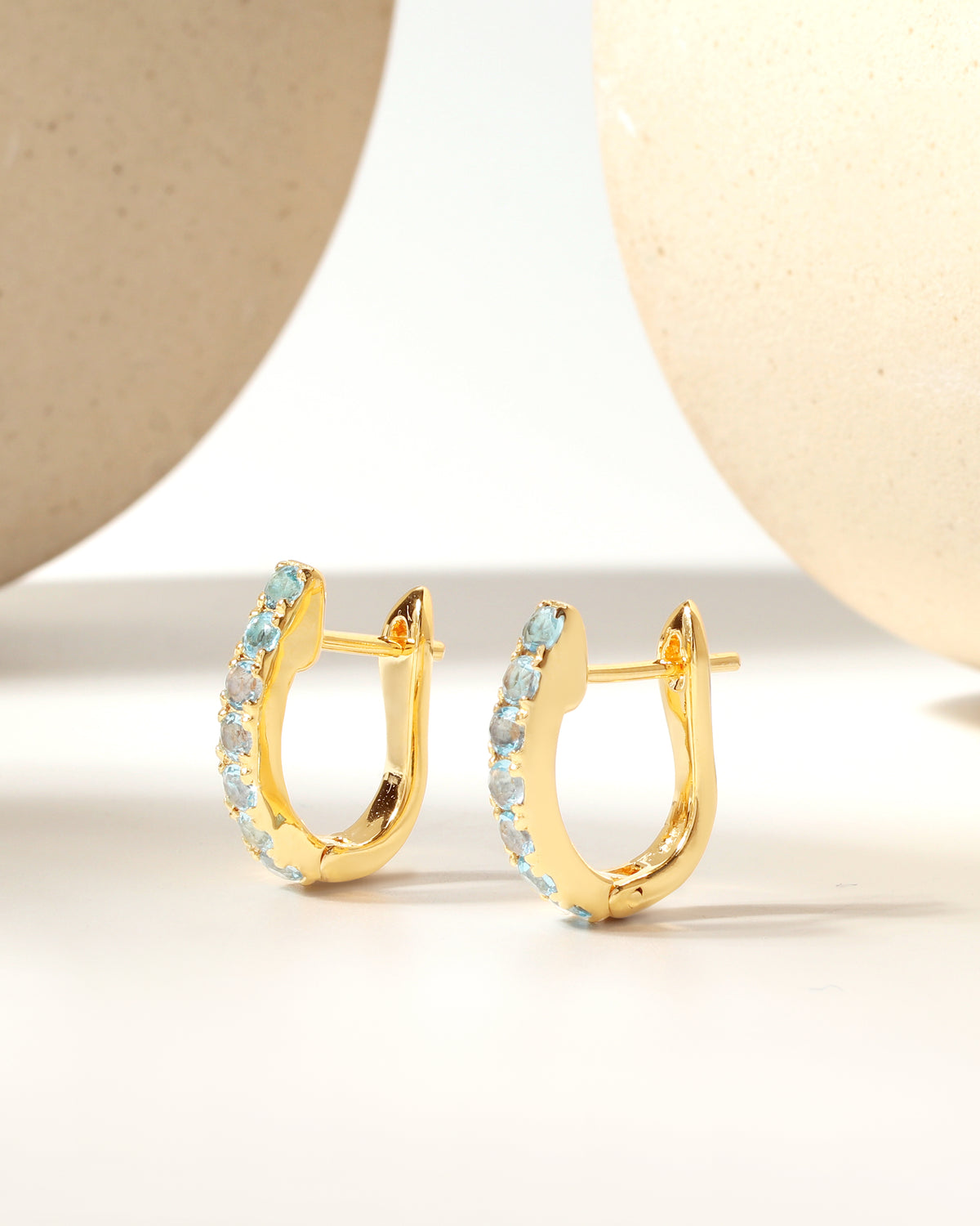 Gold huggie earrings with natural blue topaz — pair view