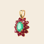 A gold pendant featuring a central oval green emerald-cut gemstone surrounded by a cluster of round red gemstones, set against a solid light beige background.