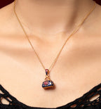 A gold chain necklace with a small handbag-shaped pendant featuring red and blue enamel detailing, shown worn on a model's neck.