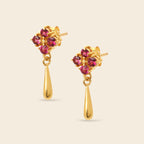A pair of gold dangle earrings with a cluster of round pink gemstones at the top and a teardrop-shaped gold drop below, shown on a light beige background.