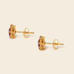 A pair of gold stud earrings with rectangular purple gemstone clusters, shown on a light beige background.