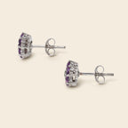Pair of silver earrings with purple gemstones on a white background