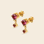 Gold earrings with red gemstones on a white background