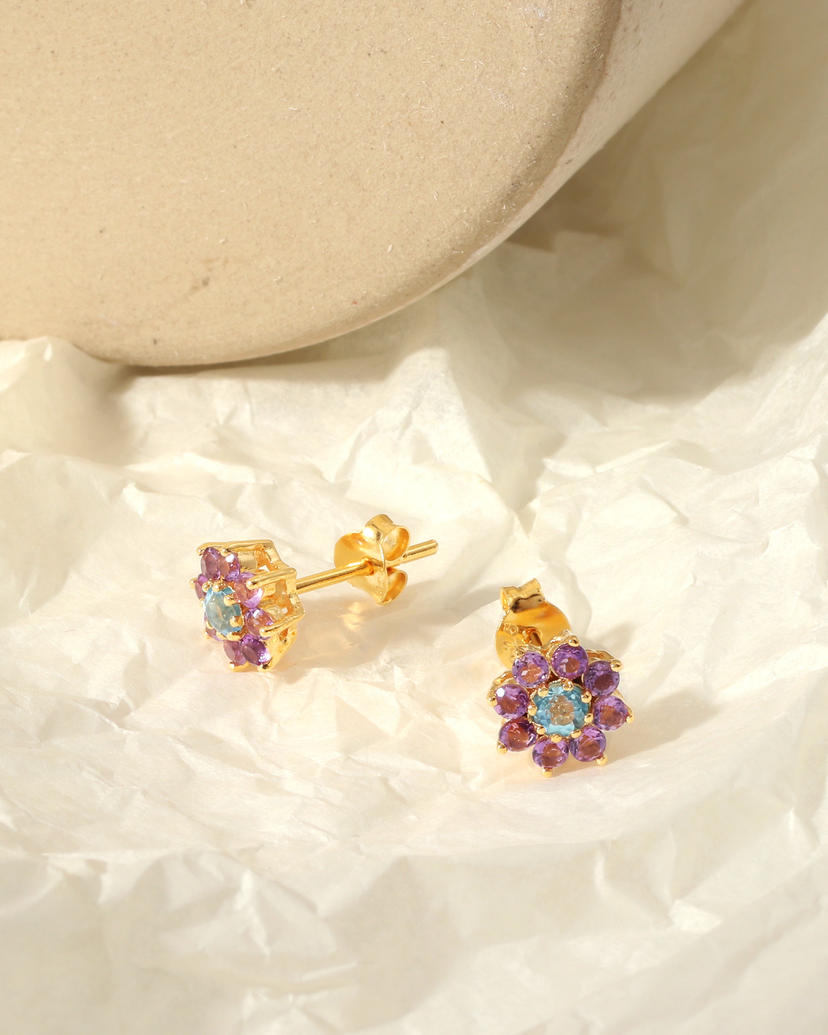 Sky-blue topaz center with amethyst petals — flower studs side view