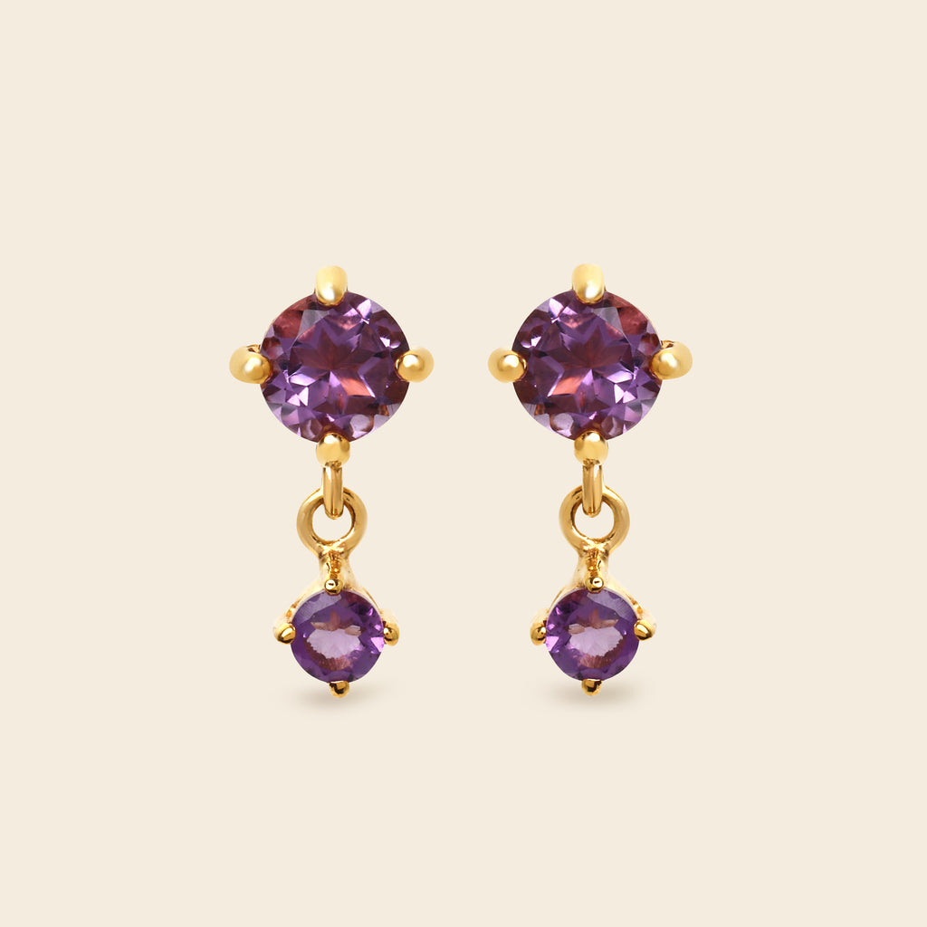 Gold earrings with purple gemstones on a white background