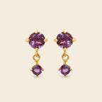 Gold earrings with purple gemstones on a white background