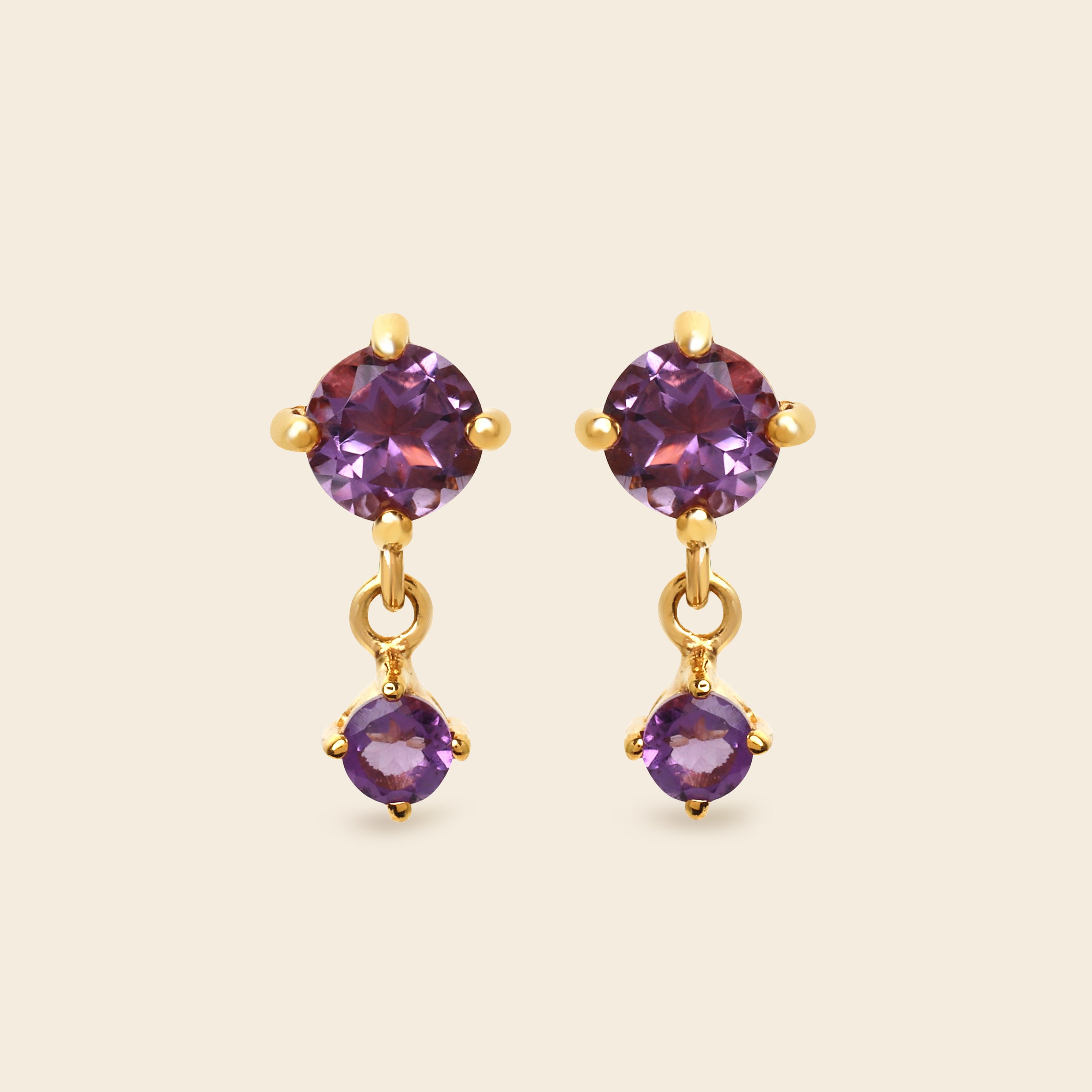 Gold earrings with purple gemstones on a white background