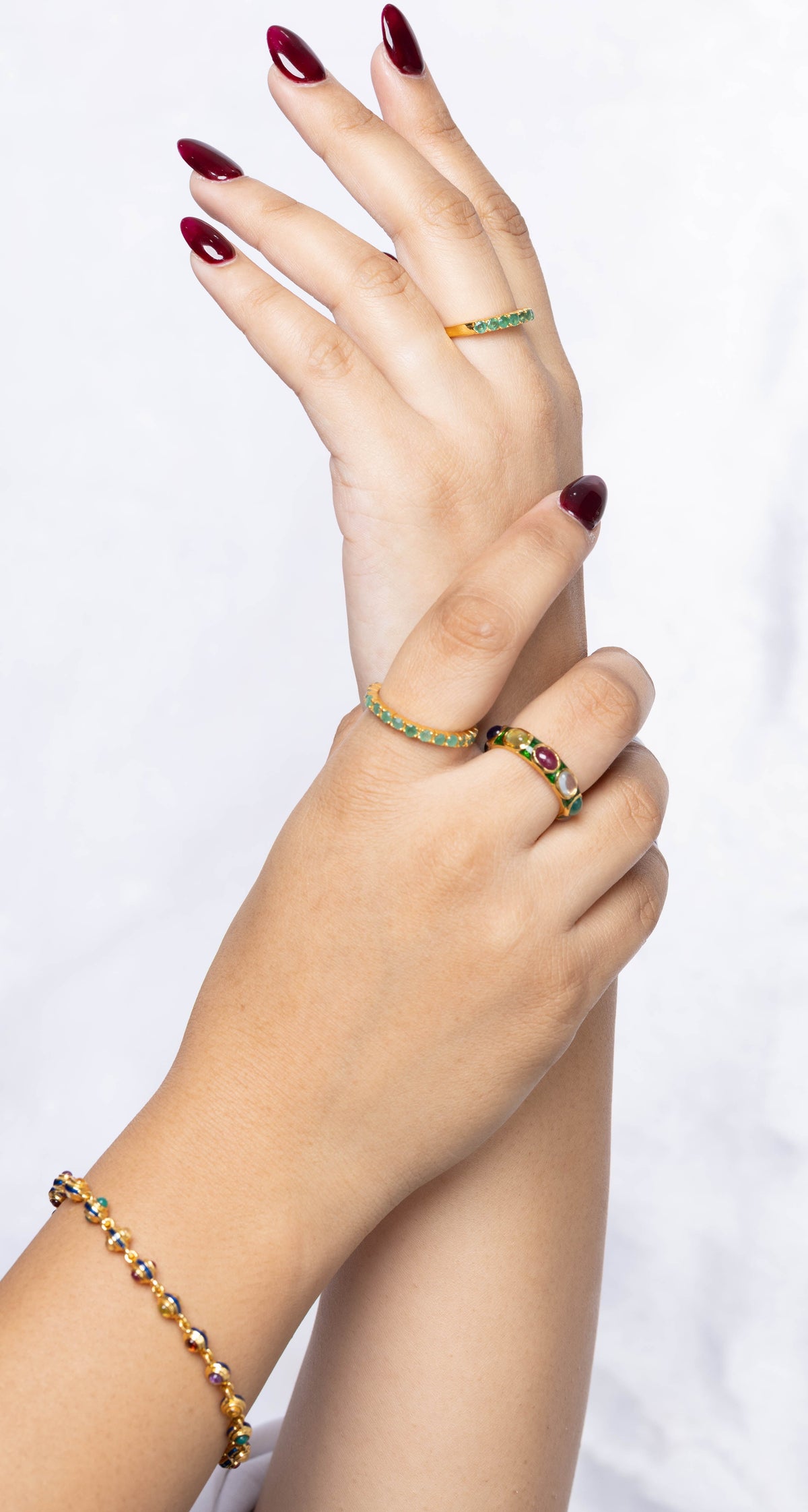 Close-up of hands with rings and a bracelet on a white background