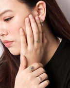 A close-up lifestyle shot of a woman wearing multiple rings and a small earring. 