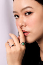 A close-up lifestyle shot of a woman wearing two rings on her fingers. 