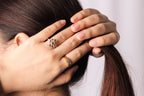 A close-up lifestyle shot of a woman's hands holding her hair, showcasing two rings.