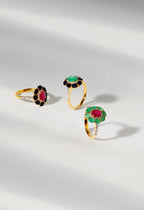 Three gold rings with gemstones on a light gray background