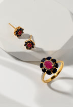 Gold ring and earrings with red and blue gemstones on a white background