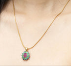 Gold necklace with floral pendant featuring ruby, emerald, and sapphire gemstones on model