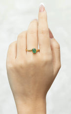 Gold ring with oval emerald gemstone on woman's hand, elegant fine jewelry design