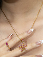 Gold snowflake pendant necklace with pink gemstones, paired with matching ring, elegant women's jewelry