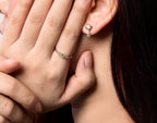 Close-up of a person wearing multiple rings and a small stud earring, with one hand covering part of the face. 