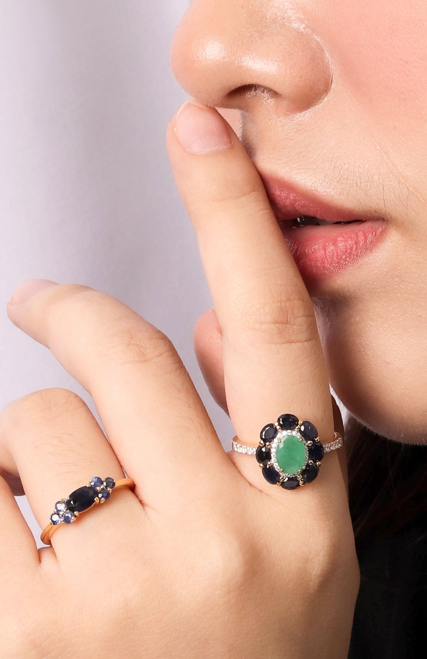 A close-up lifestyle shot of a person's hand and lower face wearing two silver rings. 