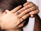 A close-up lifestyle shot of a woman's hands holding her hair, showcasing two rings.
