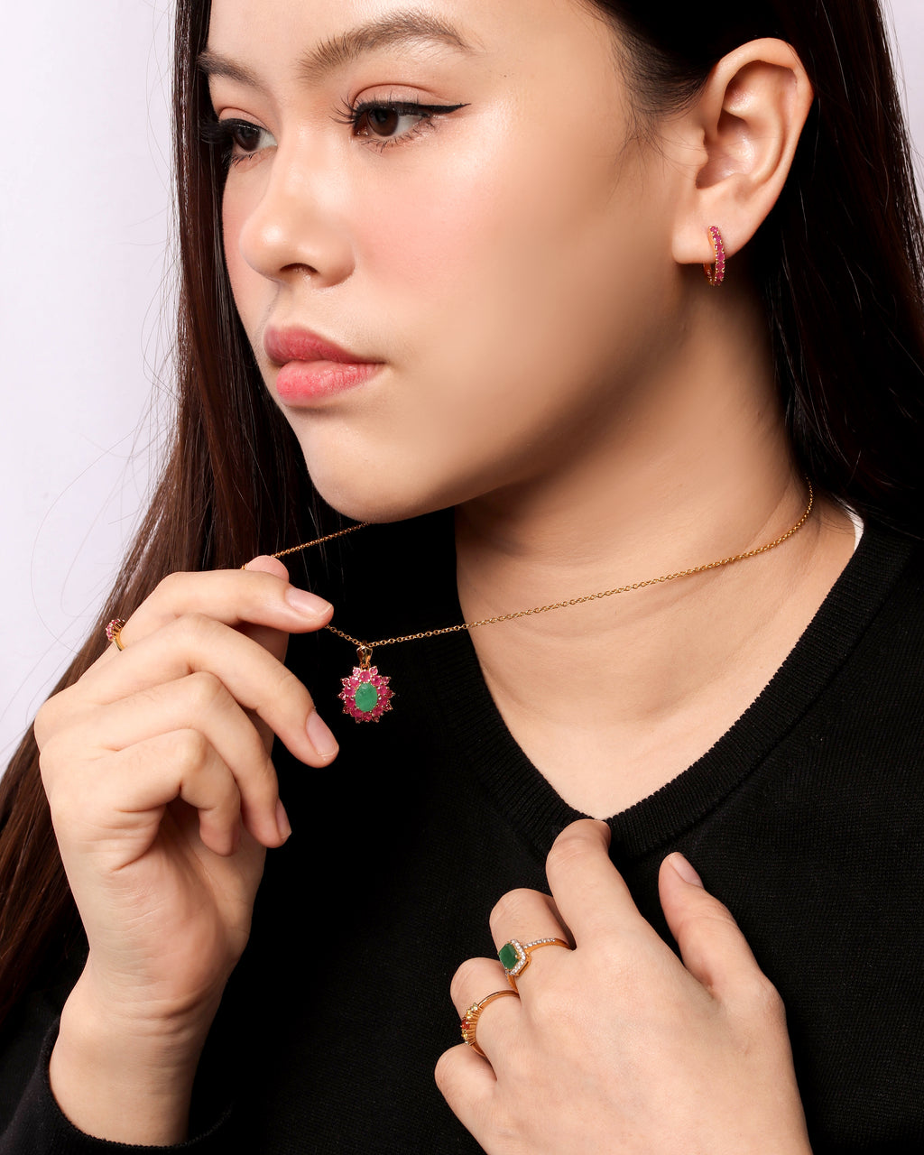 A close-up lifestyle shot of a woman wearing a delicate gold chain necklace with a small round pendant featuring a pink and green floral design. 