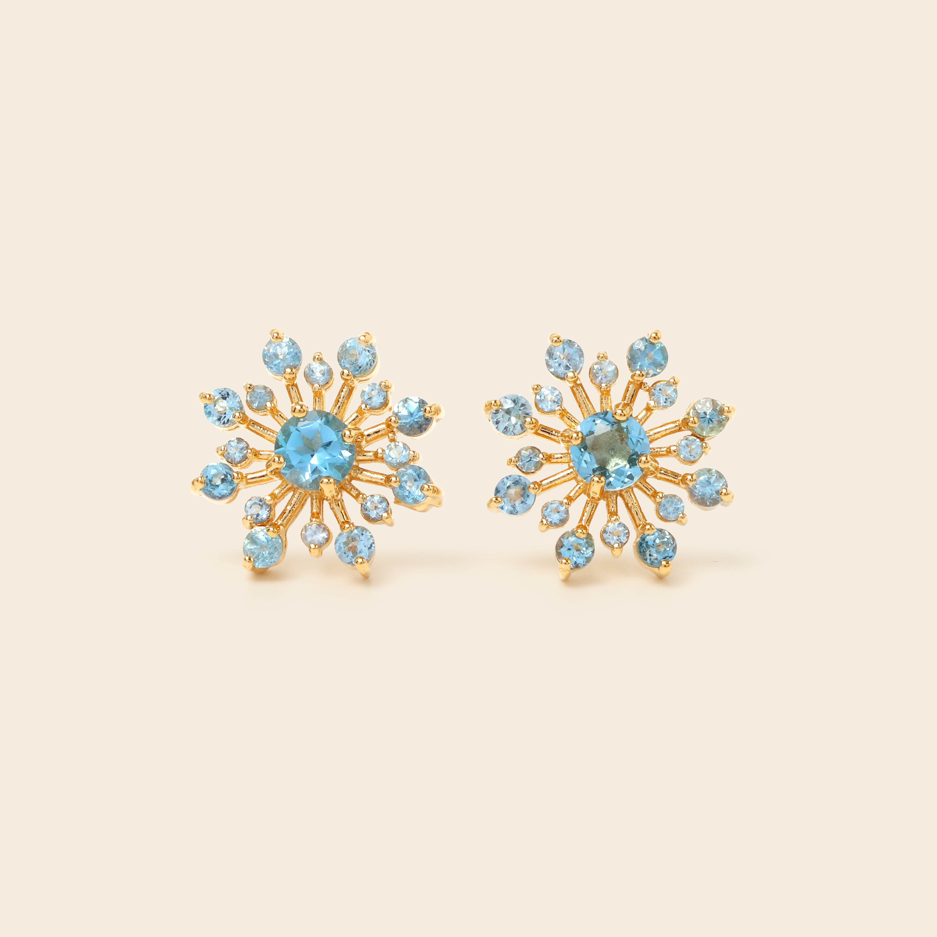 Blue topaz snowflake studs in 18K gold — detail view