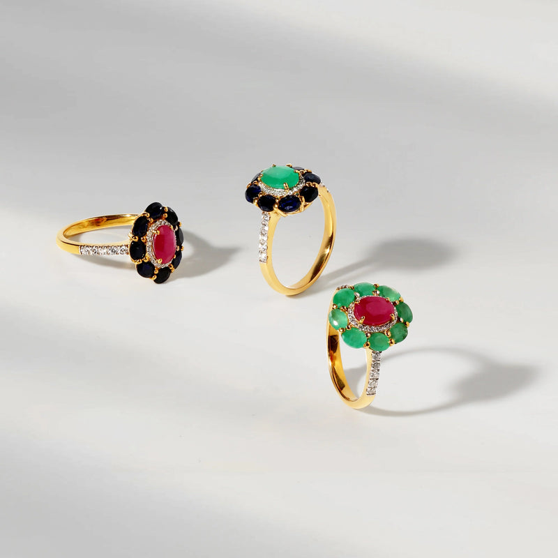 Three gold rings with gemstones on a light gray background