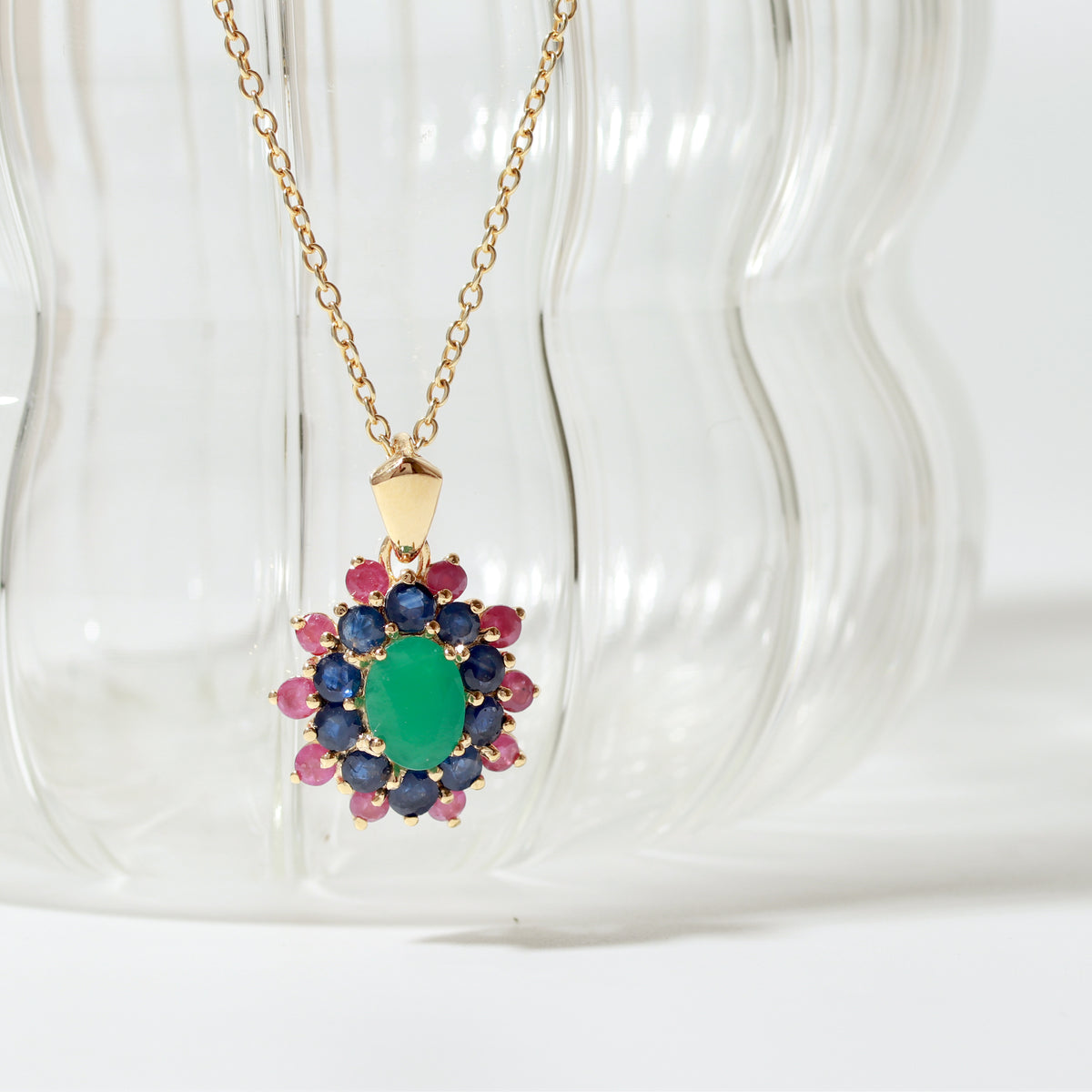 Emerald center with sapphire and ruby petals — flower pendant front view