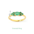 Gold emerald ring with oval center stone and smaller green gemstones, 0.5cm height